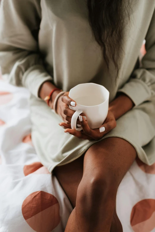 a woman sitting on a bed holding a cup, by Carey Morris, trending on unsplash, green tea, vanilla, manuka, white