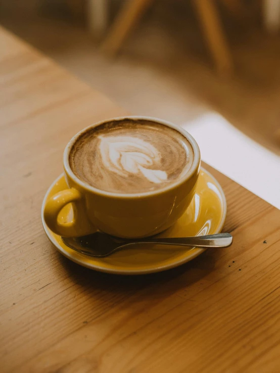a cup of coffee sitting on top of a wooden table, yellow hue, profile image, vanilla, multiple stories