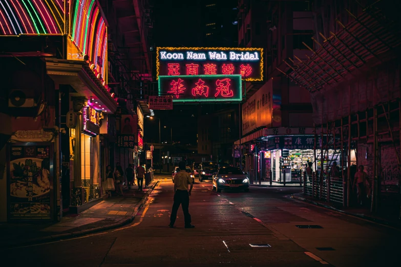 a man standing in the middle of a street at night, inspired by Liam Wong, pexels contest winner, pixel art, kowloon walled city, bright signage, people at night