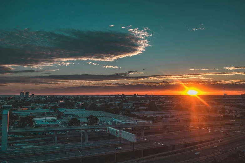 a view of the sun setting over a city, a picture, by Ryan Pancoast, unsplash contest winner, teal sky, wide high angle view, long beach background, albuquerque