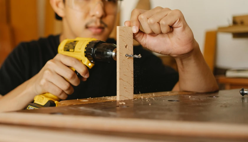 a man working on a piece of wood with a drill, trending on pexels, arts and crafts movement, asian male, rectangle, “hyper realistic, hand