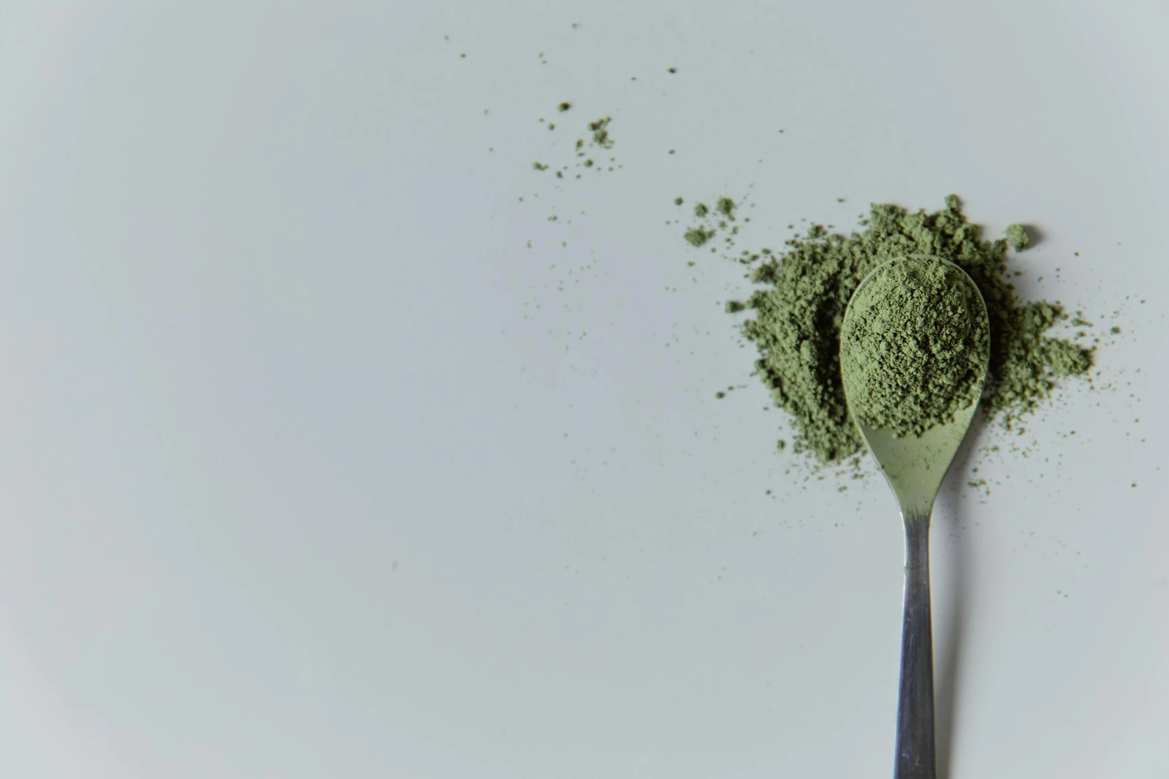 a spoon filled with green powder on top of a white surface, trending on unsplash, hurufiyya, background image, japanese collection product, hemp, animation