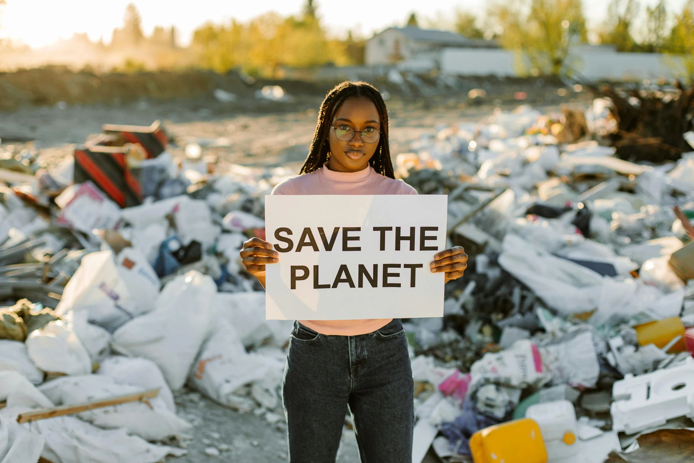 a woman holding a sign that says save the planet, an album cover, by Julia Pishtar, pexels contest winner, plasticien, landfill, african american young woman, avatar image, 2077