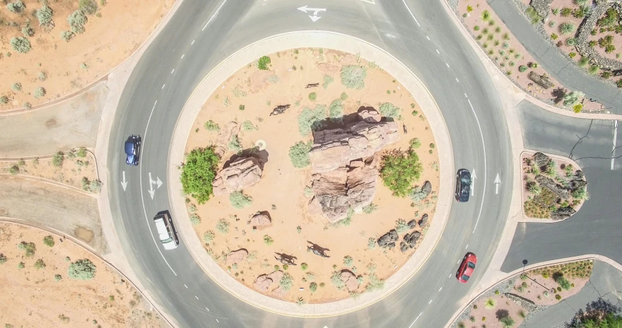 an aerial view of a road in the desert, by Lee Loughridge, pexels contest winner, photorealism, everything enclosed in a circle, car jumping, extreme panoramic, helipad