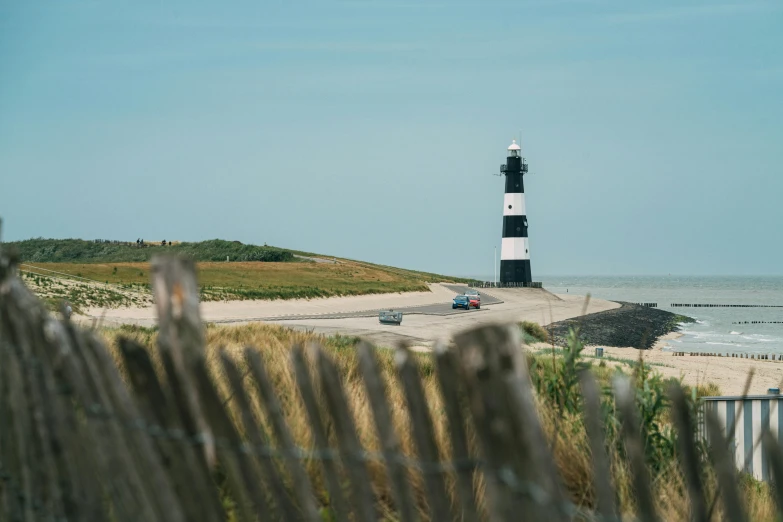 a white and black lighthouse sitting on top of a sandy beach, by Adam Pijnacker, pexels contest winner, a road leading to the lighthouse, seen from a distance, 15081959 21121991 01012000 4k, extra high resolution