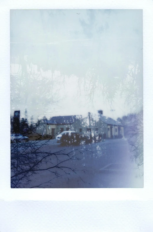 a polaroid picture of a street with buildings in the background, by Anson Maddocks, impressionism, ghostly white trees, blue image, in dunwall, snowcrash