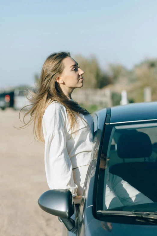 a woman leaning on the door of a car, trending on unsplash, slightly sunny weather, knight of cups, low quality photo, mild breeze wind
