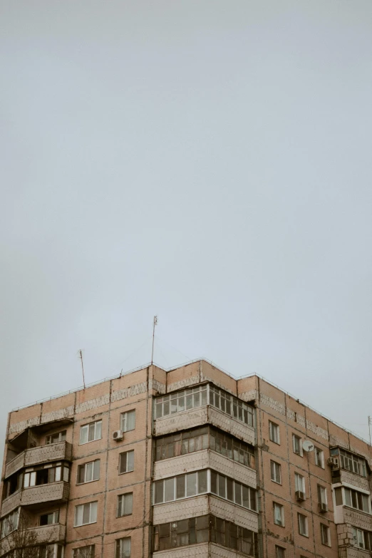 a tall building sitting on the side of a road, by Attila Meszlenyi, gray sky, soviet town, high quality photo, 256x256