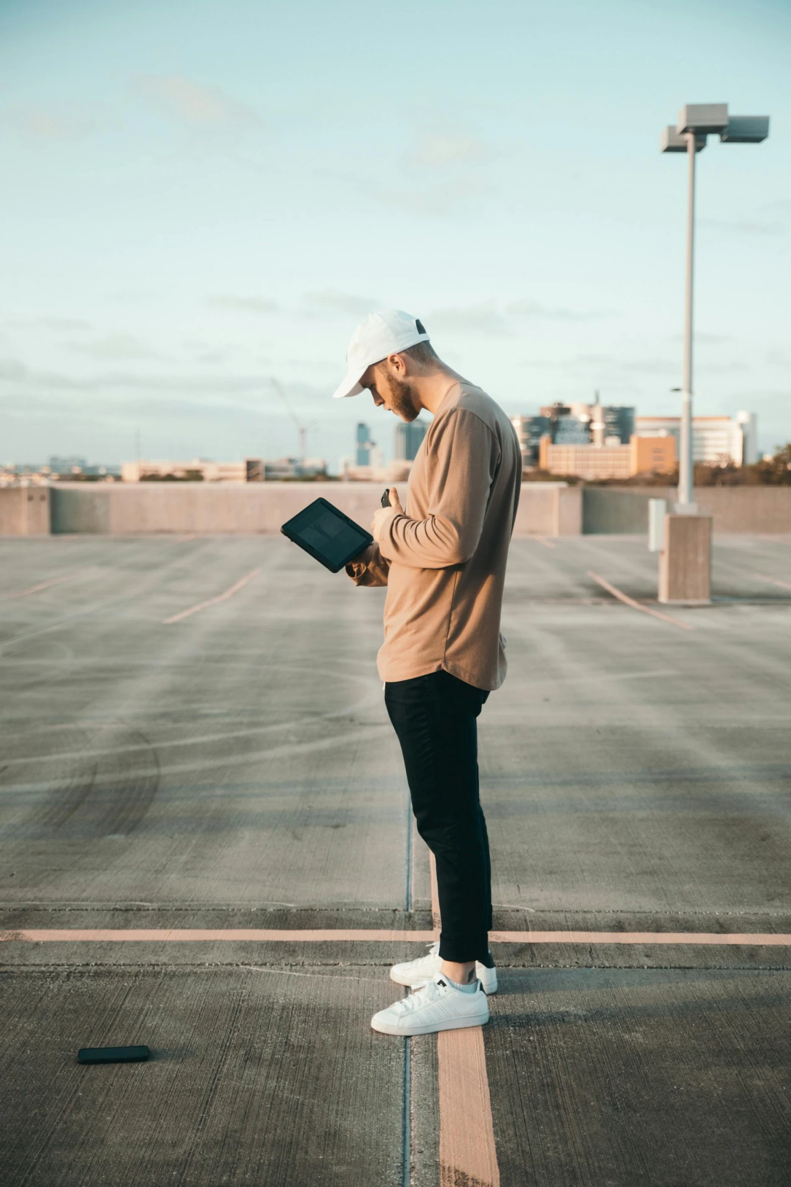 a man standing on top of a parking lot holding a laptop, by Carey Morris, pexels contest winner, reading a book, pray, modern casual clothing, gif