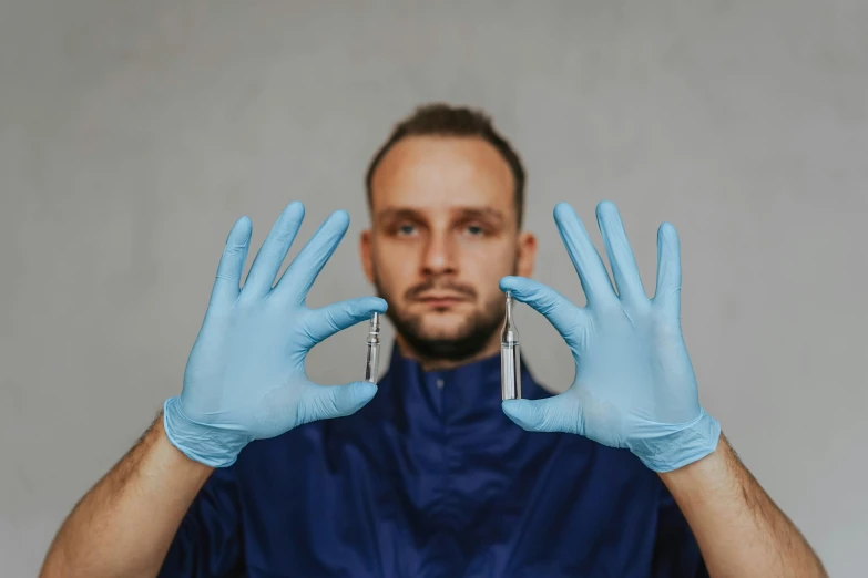 a man holding a pair of blue gloves in front of his face, by Adam Marczyński, pexels contest winner, hyperrealism, syringes, gauged ears, surgical equipment, avatar image