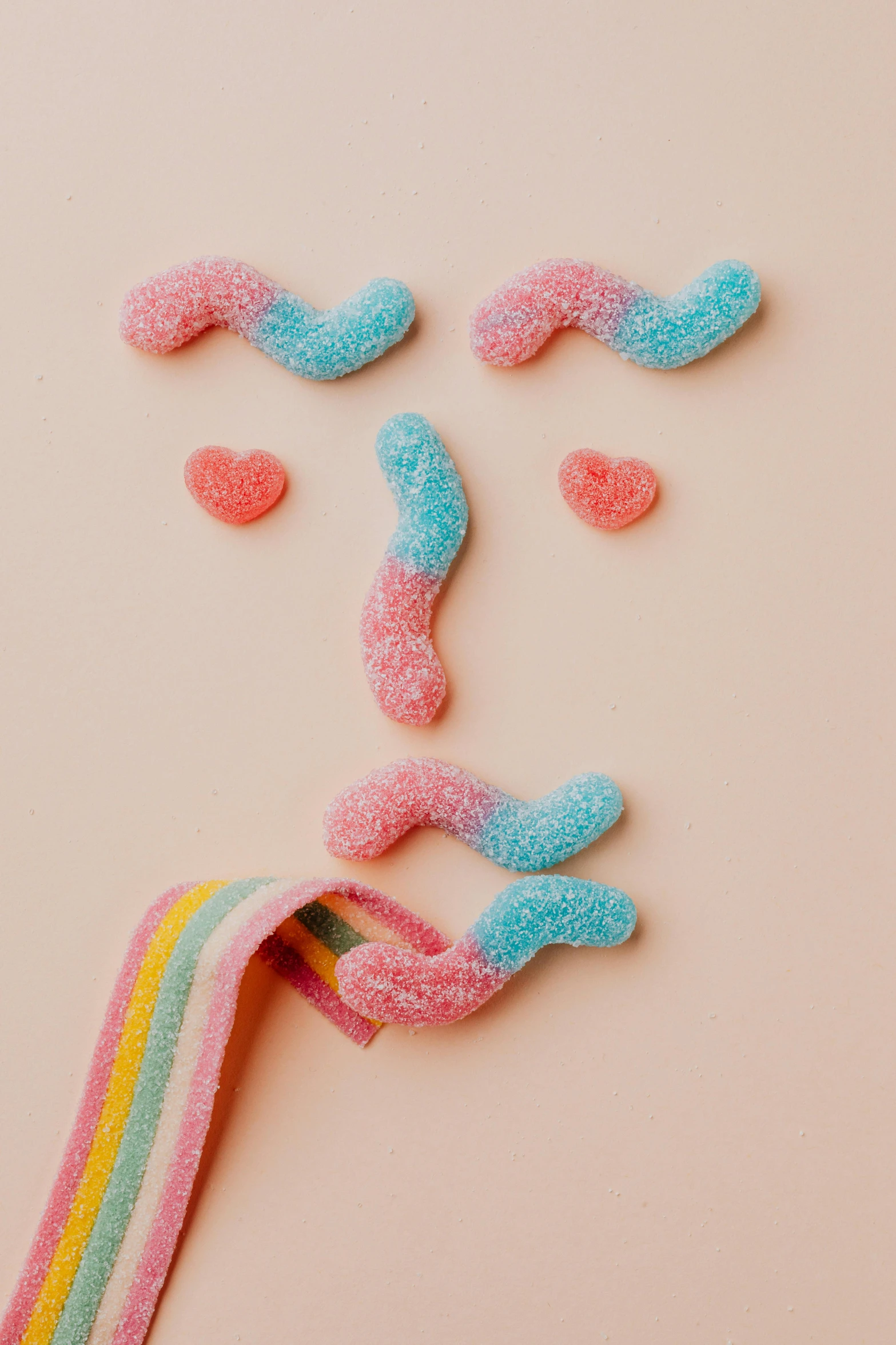 a face made out of candy on a pink background, by Rachel Reckitt, gummy worms, on a gray background, soft mood, corduroy