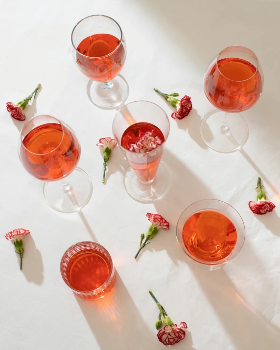 a group of wine glasses sitting on top of a table, inspired by Jacopo Bellini, pexels contest winner, renaissance, pink orange flowers, flatlay, pale red, iced tea glass