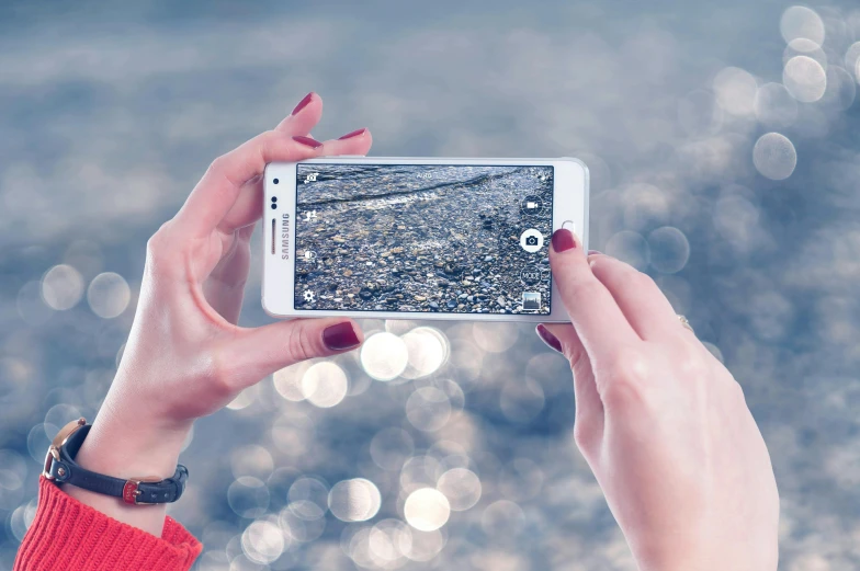 a woman taking a picture with her cell phone, a picture, by Lucia Peka, pexels contest winner, at the seaside, bokeh. rule of thirds, flatlay, the image is futuristic