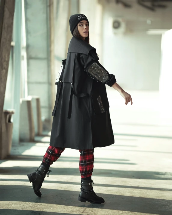 a woman in a black coat and plaid pants, unsplash, stylised military clothes, wearing black hooded cloak, promo image, model is wearing techtical vest