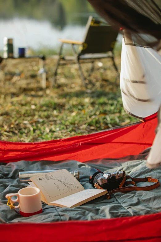 a person laying in a hammock with a cup of coffee, barrel fires and tents, red pennants, field notes, crimson themed