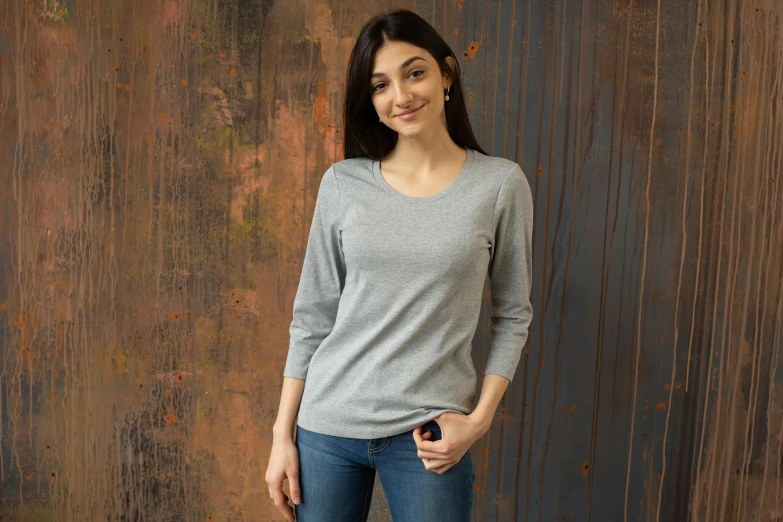 a woman standing in front of a rusty wall, a portrait, shutterstock contest winner, renaissance, gray shirt, detailed product image, on wooden table, no - text no - logo