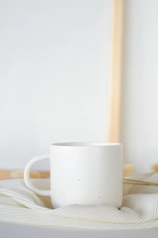 a white coffee cup sitting on top of a table, a minimalist painting, trending on unsplash, minimalism, ink dots, matte white background, promo image, cozy studio photography