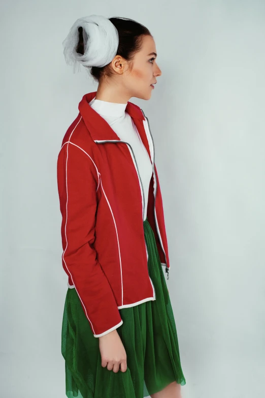 a woman in a red jacket and green skirt, an album cover, inspired by Oswaldo Viteri, pexels contest winner, red sport clothing, ( side ) profile, vintage aesthetic, issey miyake