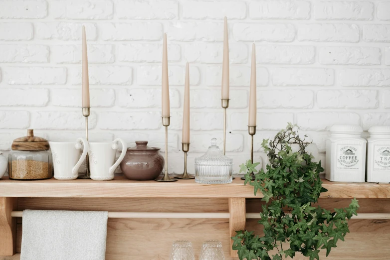 a potted plant sitting on top of a wooden shelf, white candles, cutlery, in a row, detailed product image