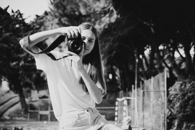 a black and white photo of a woman holding a camera, a black and white photo, unsplash, dslr photo of a pretty teen girl, anna nikonova aka newmilky, !! low contrast!!, medium format