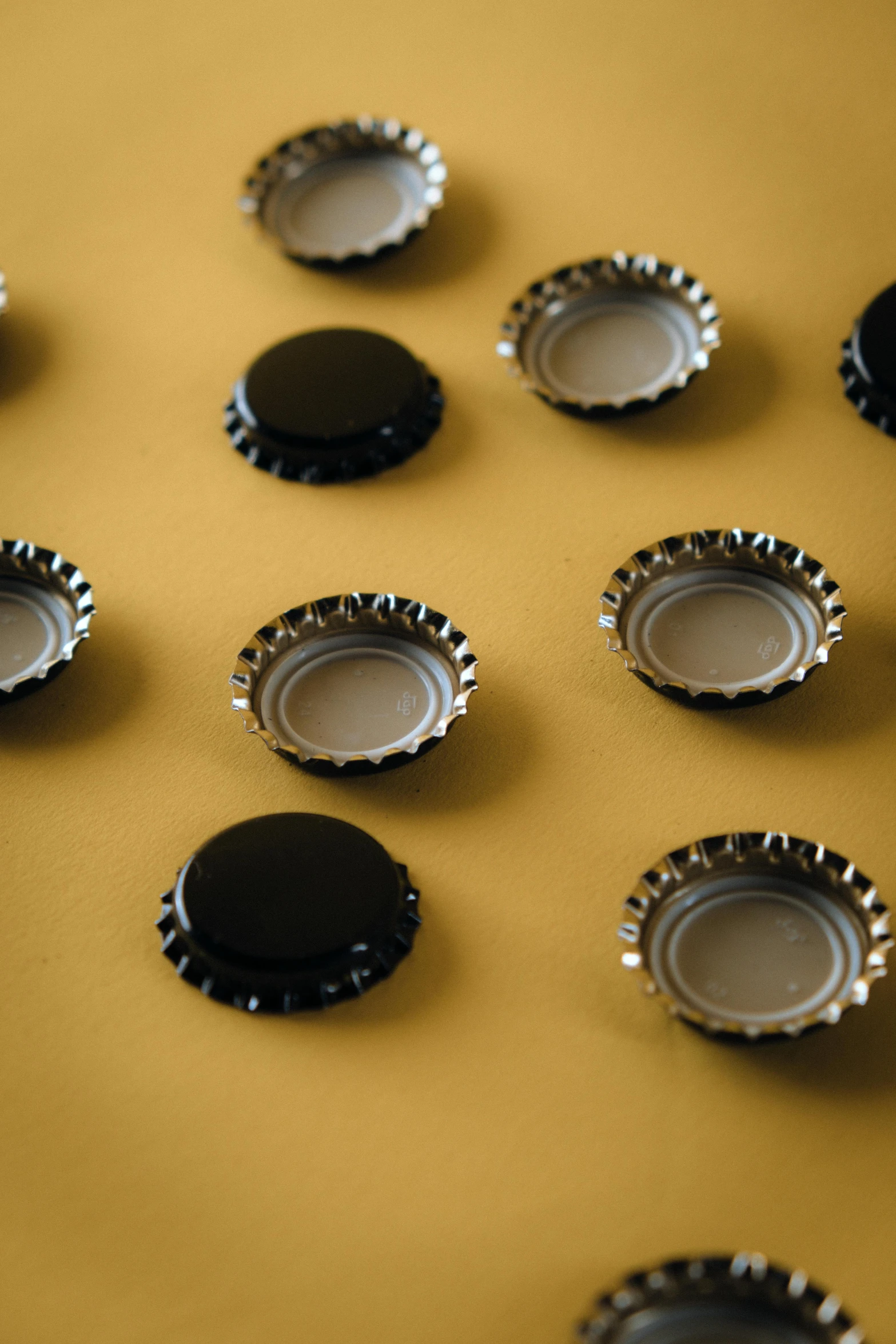 a bunch of bottle caps sitting on top of a table, pexels, black and yellow scheme, sleek round shapes, panel of black, caramel