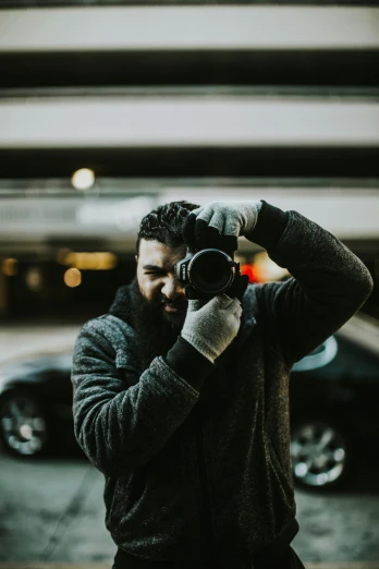 a man taking a picture with a camera, standing in a parking lot, man wearing a closed cowl, portrait featured on unsplash, a portrait of rahul kohli
