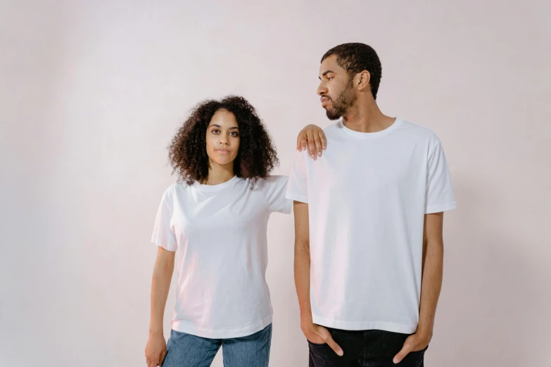 a man and a woman standing next to each other, by Carey Morris, pexels, white tshirt, pearlescent white, varying ethnicities, thumbnail