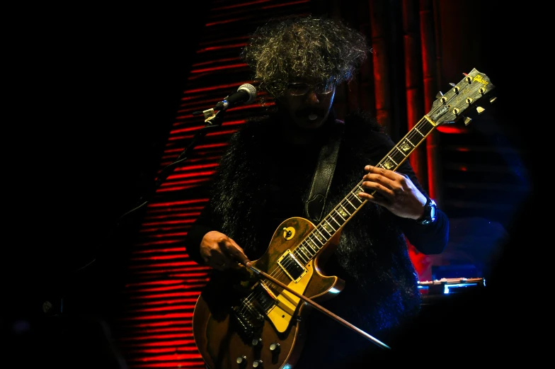 a man playing a guitar in front of a microphone, an album cover, pexels, vanitas, playing guitar onstage, neil gaiman, atoms, profile image