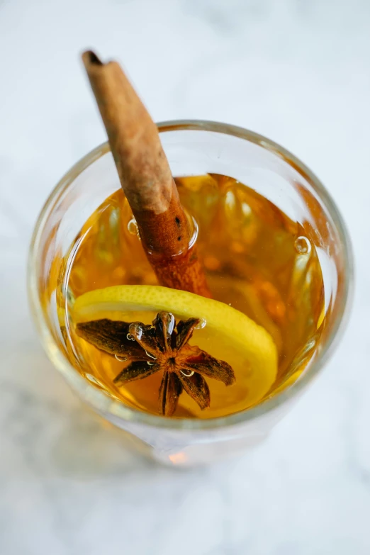 a glass of tea with a cinnamon stick sticking out of it, citrinitas, molten, up close, half moon