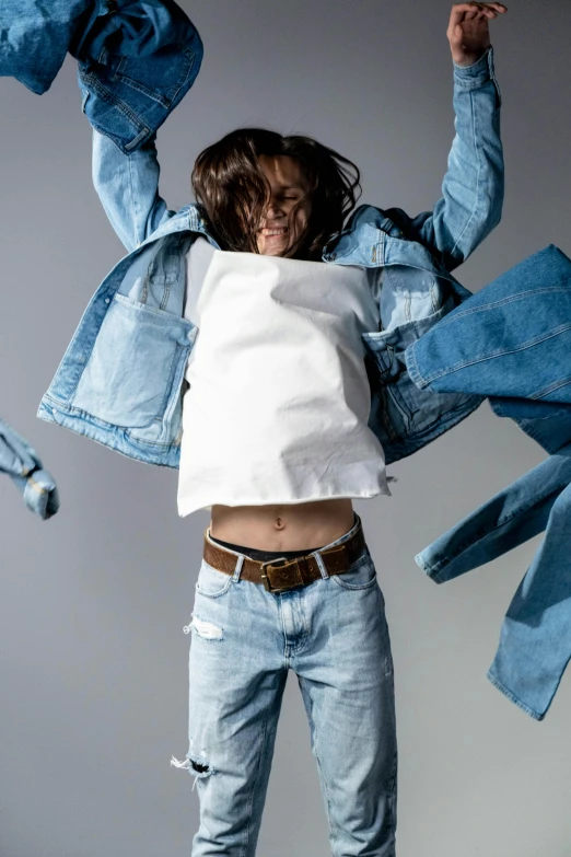 a man jumping in the air with his hands in the air, an album cover, inspired by Fei Danxu, trending on pexels, denim jacket, bedhead, ripped up white garment, non binary model