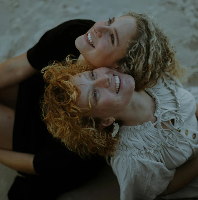 a couple of women laying on top of each other, trending on pexels, renaissance, short curly blonde haired girl, highly detailed photo of happy, beach pic, ginger hair with freckles