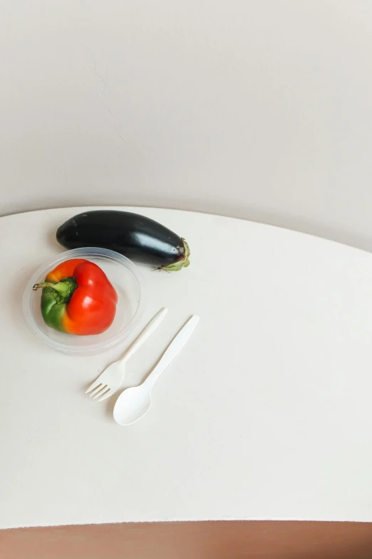 a white table topped with a bowl of fruit and vegetables, by Jang Seung-eop, superflat, eggplant, simplistic, product image, black fork