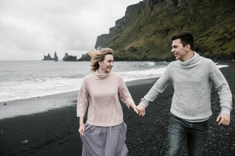 a man and woman walking on a black sand beach, by Hallsteinn Sigurðsson, pexels contest winner, renaissance, flirting smiling, sweater, promotional image