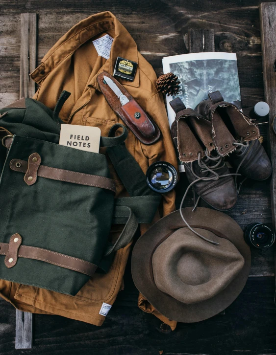 a backpack sitting on top of a wooden bench, ferred - themed robes and hat, field notes, rugged ranger, flatlay