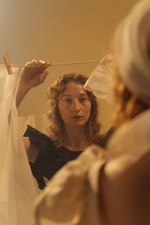 a woman that is standing in front of a mirror, a portrait, inspired by Marie Laurencin, renaissance, perfectly lit. movie still, curls, fully covered in drapes, production photo