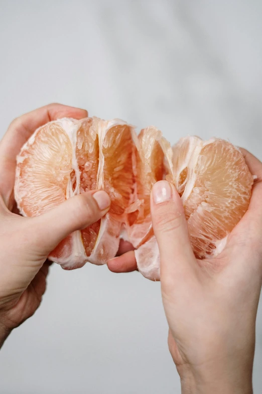 a person holding a peeled orange in their hands, by Emily Shanks, skinned, sliced grapefruit, jelly - like texture, carefully crafted