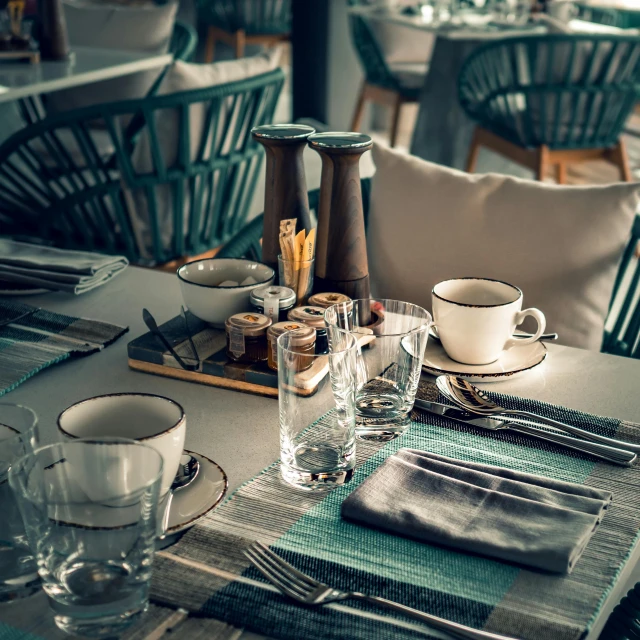 a table that has a bunch of place settings on it, by Adam Marczyński, pexels contest winner, renaissance, desaturated color, coffee shop, brown and cyan blue color scheme, restaurant