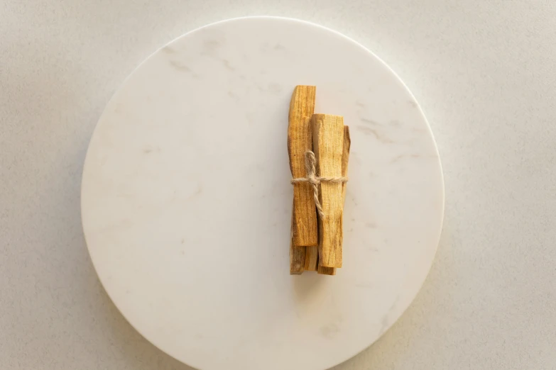 a piece of wood sitting on top of a white plate, unsplash, tiny sticks, on a marble pedestal, cinnamon, detailed product image
