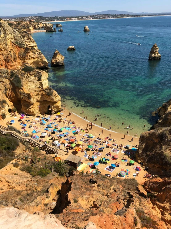 a beach filled with lots of people next to the ocean, portugal, chiseled formations, overlooking the ocean, slide show