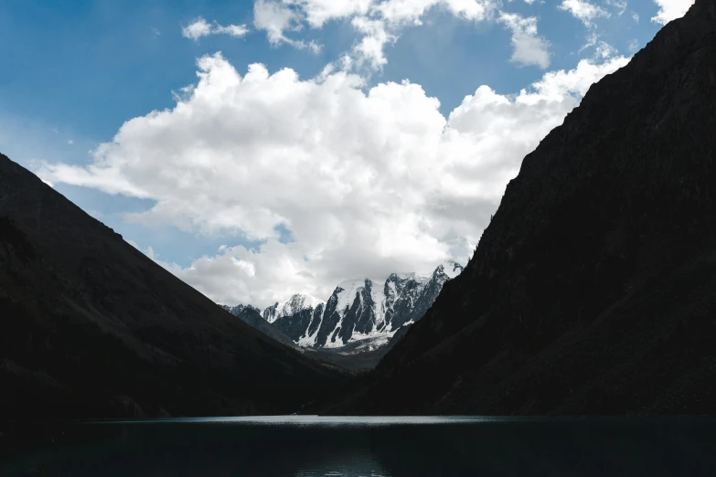 a body of water surrounded by mountains under a cloudy sky, an album cover, pexels contest winner, hurufiyya, andes, ash thorp khyzyl saleem, white clouds, grey