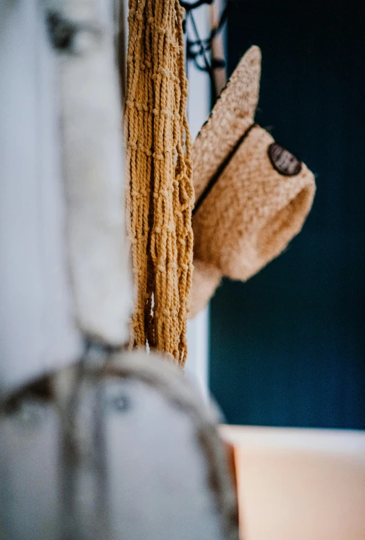 a brown hat sitting on top of a window sill, inspired by Toss Woollaston, unsplash, scarf made from spaghetti, hanging rope, close up shot from the side, sustainable materials