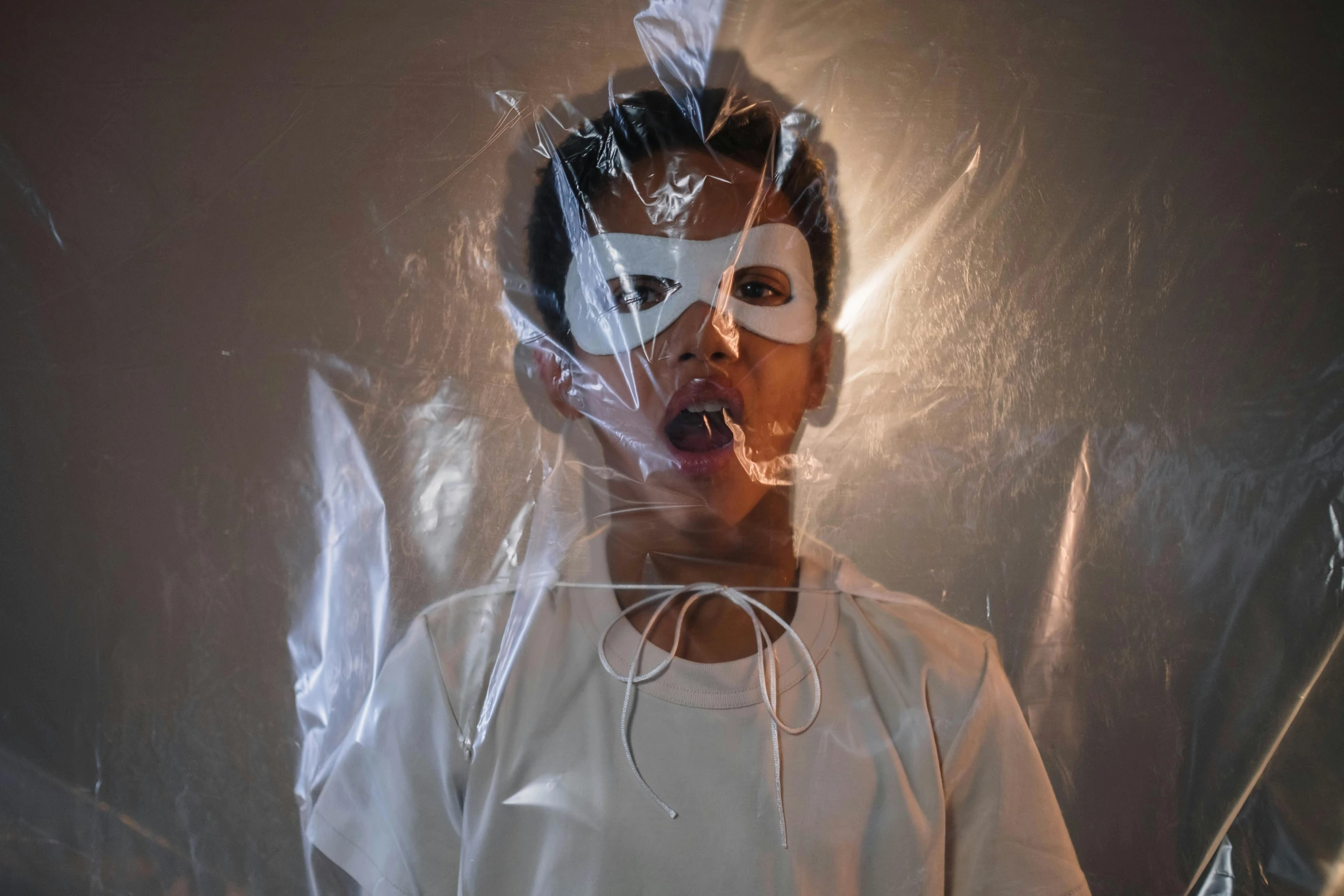 a close up of a person wearing a mask, an album cover, pexels contest winner, conceptual art, wearing translucent sheet, young boy, with wires and bandages, claustrophobic room