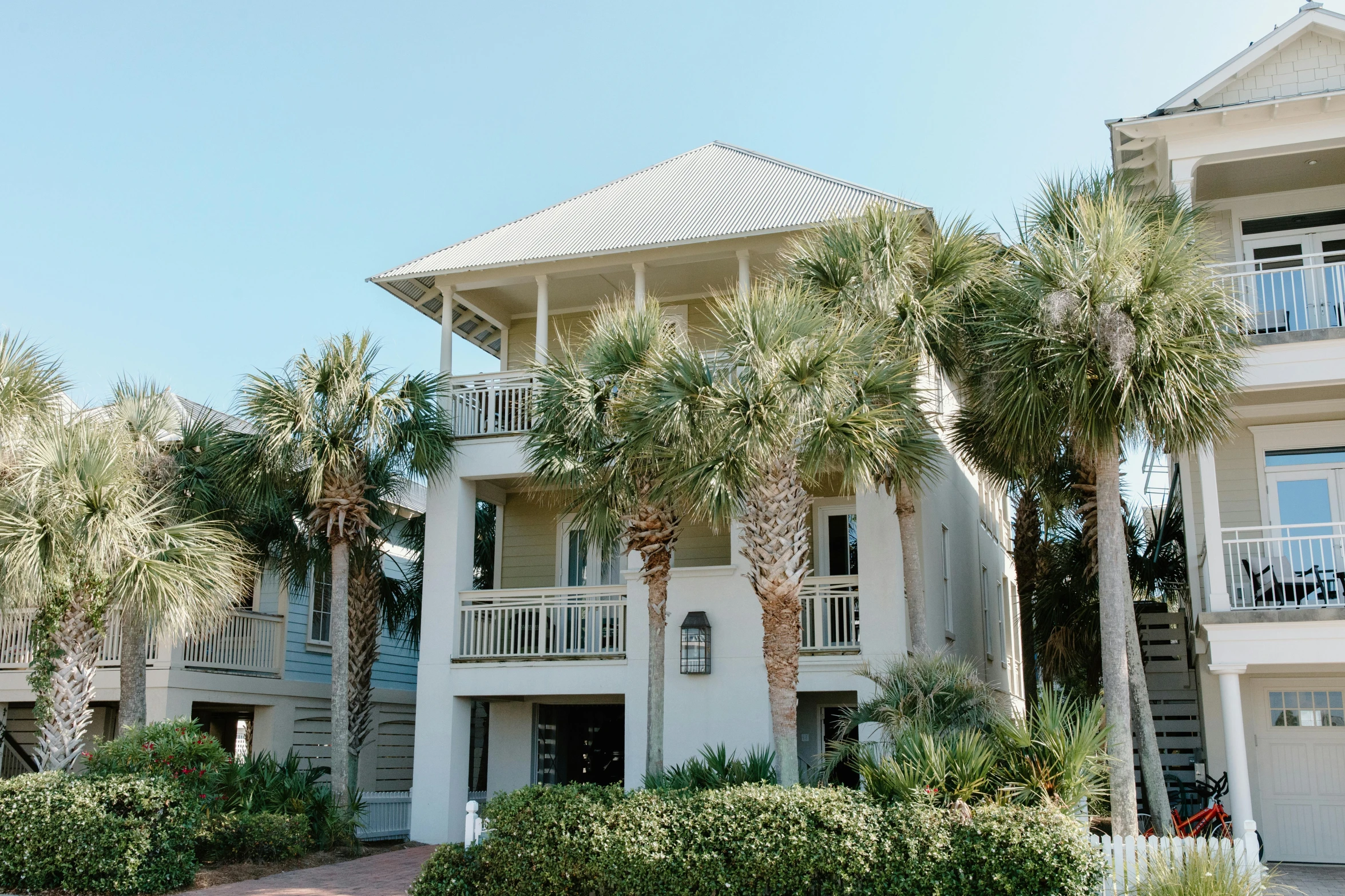 a building with palm trees in front of it, by Carey Morris, unsplash, the emerald coast, with a front porch, square, silver，ivory