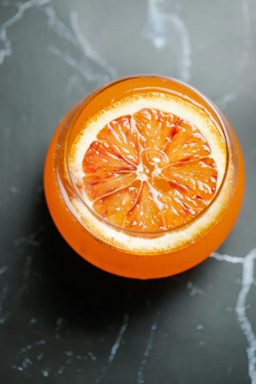 an orange cut in half sitting on a table, by Tuvia Beeri, infused, epicurious, vermillion, top down shot