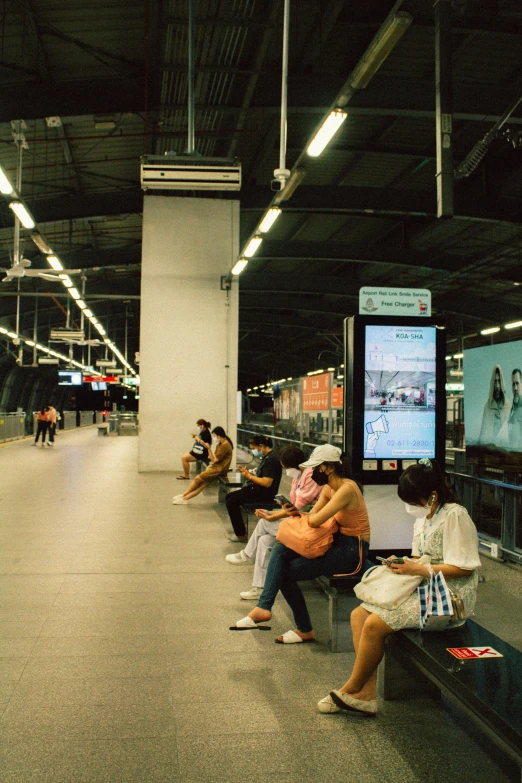 a group of people sitting on a bench in a train station, tithi luadthong, technological screens, 2 5 6 x 2 5 6 pixels, taken in 2 0 2 0