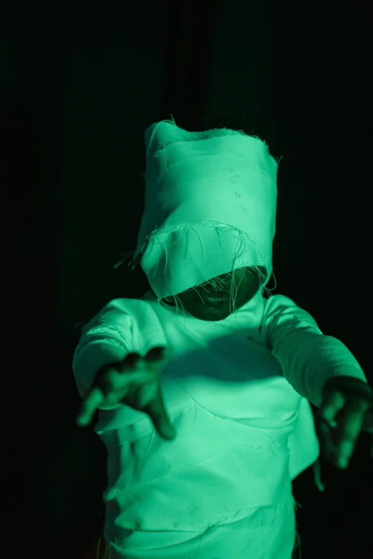 a person in a costume holding a tennis racquet, a hologram, inspired by Bruce Nauman, unsplash, children born as ghosts, soft green lighting, hooded figures, mummy
