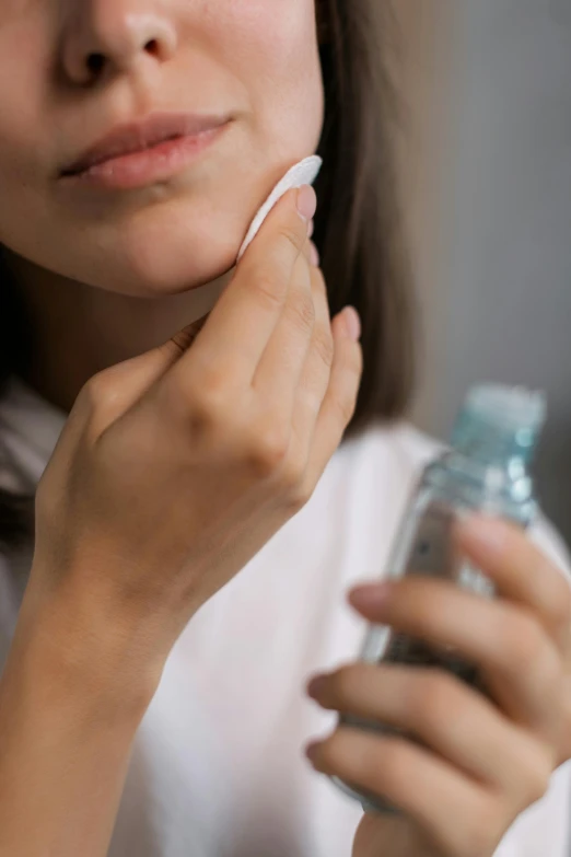 a woman brushing her teeth with a toothbrush, by Adam Marczyński, noticeable tear on the cheek, holding a bottle, square, pimples