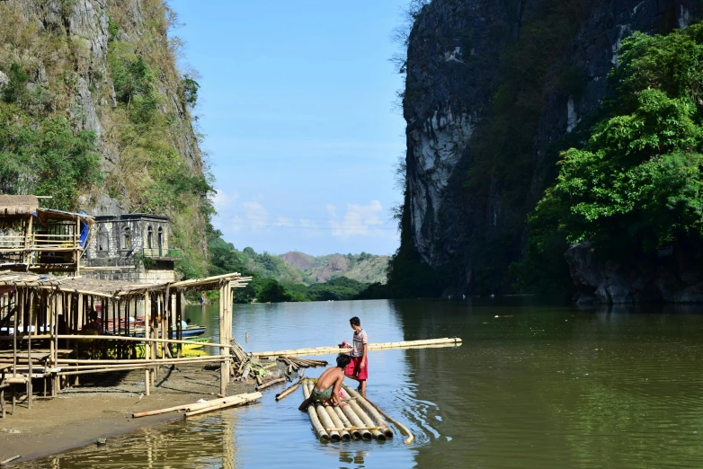 a couple of people that are on a raft in the water, by Jessie Algie, pexels contest winner, hurufiyya, philippines, limestone, bamboo, view from the side