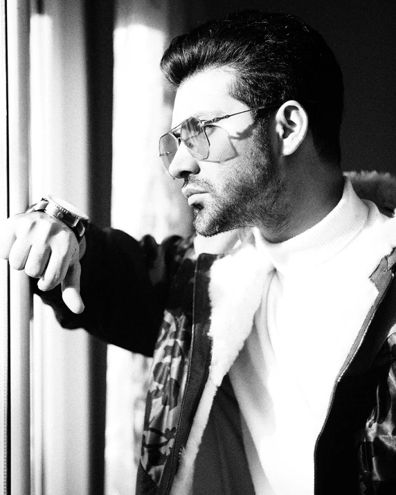 a black and white photo of a man looking out a window, by Niyazi Selimoglu, trending on pexels, renaissance, wearing versace sunglasses, zachary quinto, wearing a fancy jacket, an all white human