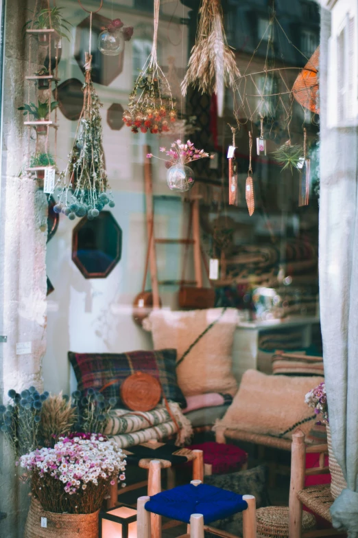 a living room filled with lots of furniture and plants, a colorized photo, trending on unsplash, arts and crafts movement, shop window for magical weapons, brown and pink color scheme, sitting with flowers, hanging